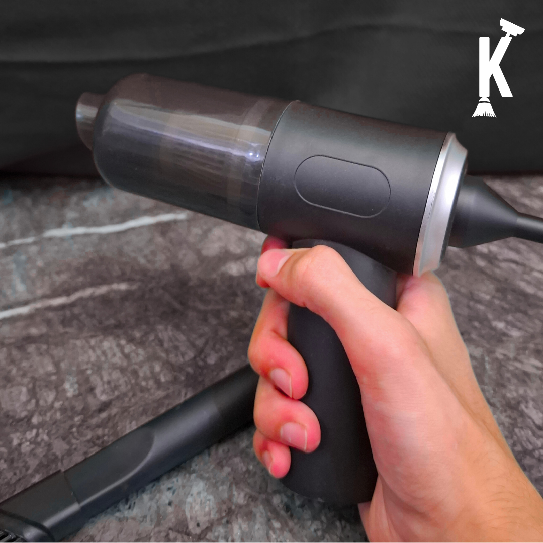 Hand holding vacuum cleaner on a textured surface with a brand logo in the corner.