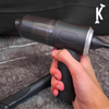 Hand holding vacuum cleaner on a textured surface with a brand logo in the corner.